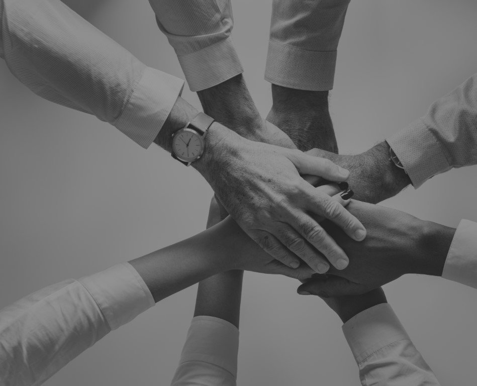 Eight hands, of different people, stacked one on another in the middle of a circle